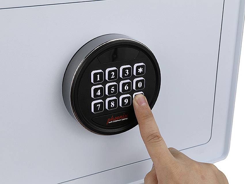 'Eine Hand drückt eine Taste auf dem Tastenfeld eines elektronischen Tresors.'