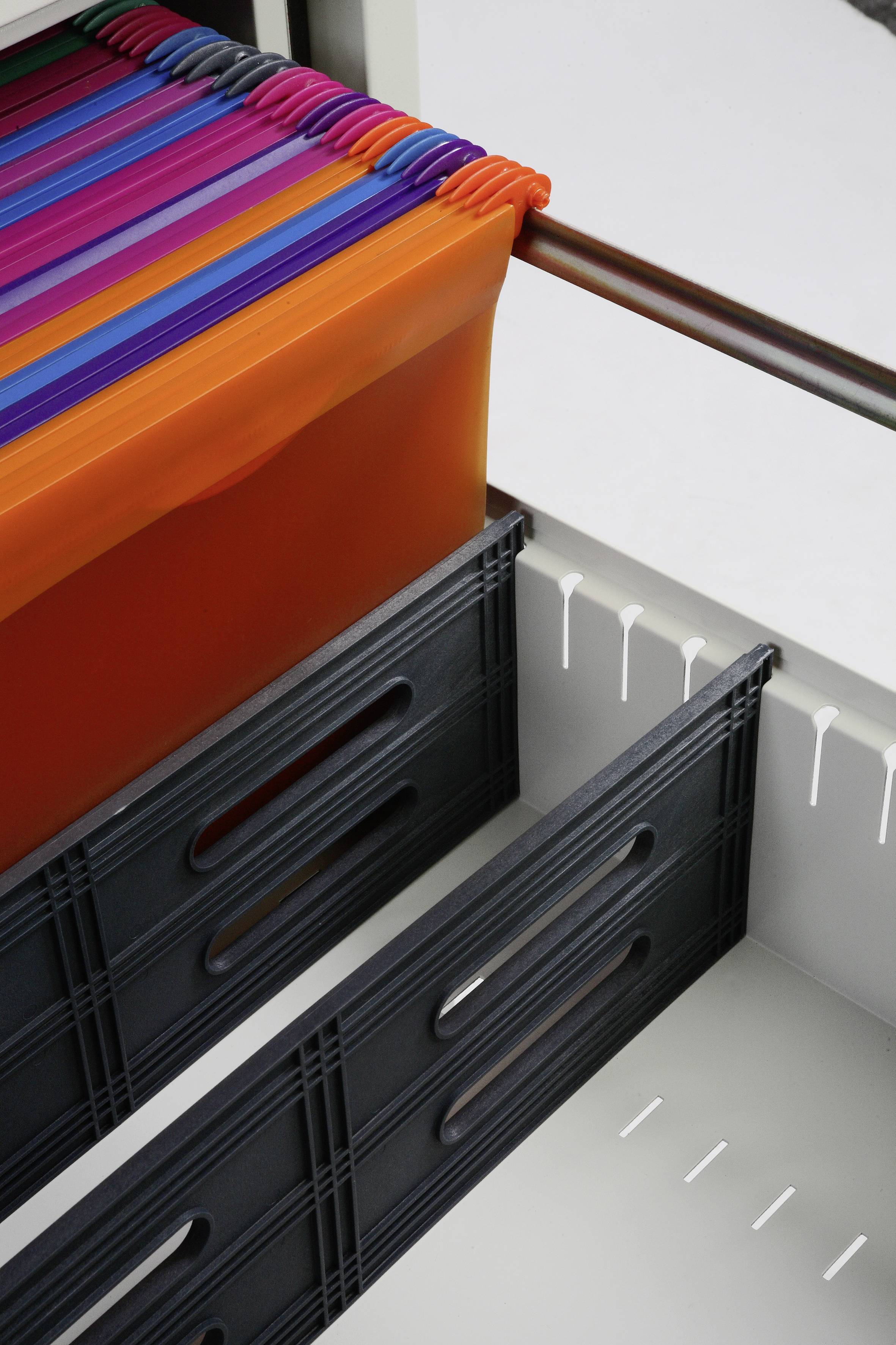 Bunte Hängeordner in einem offenen Aktenschrank, sortiert nach Farben von Orange bis Lila. Systematische Aktenorganisation.