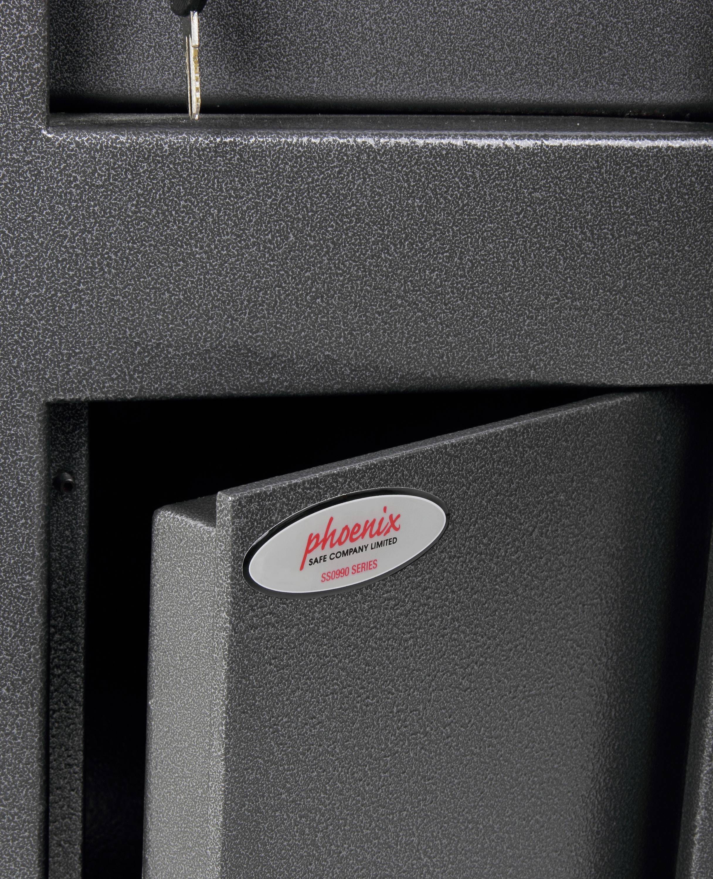Ein grauer Safe mit der Aufschrift 'phoenix safe company' ist teilweise geöffnet. Oben ist ein Schlüssel im Schloss sichtbar.