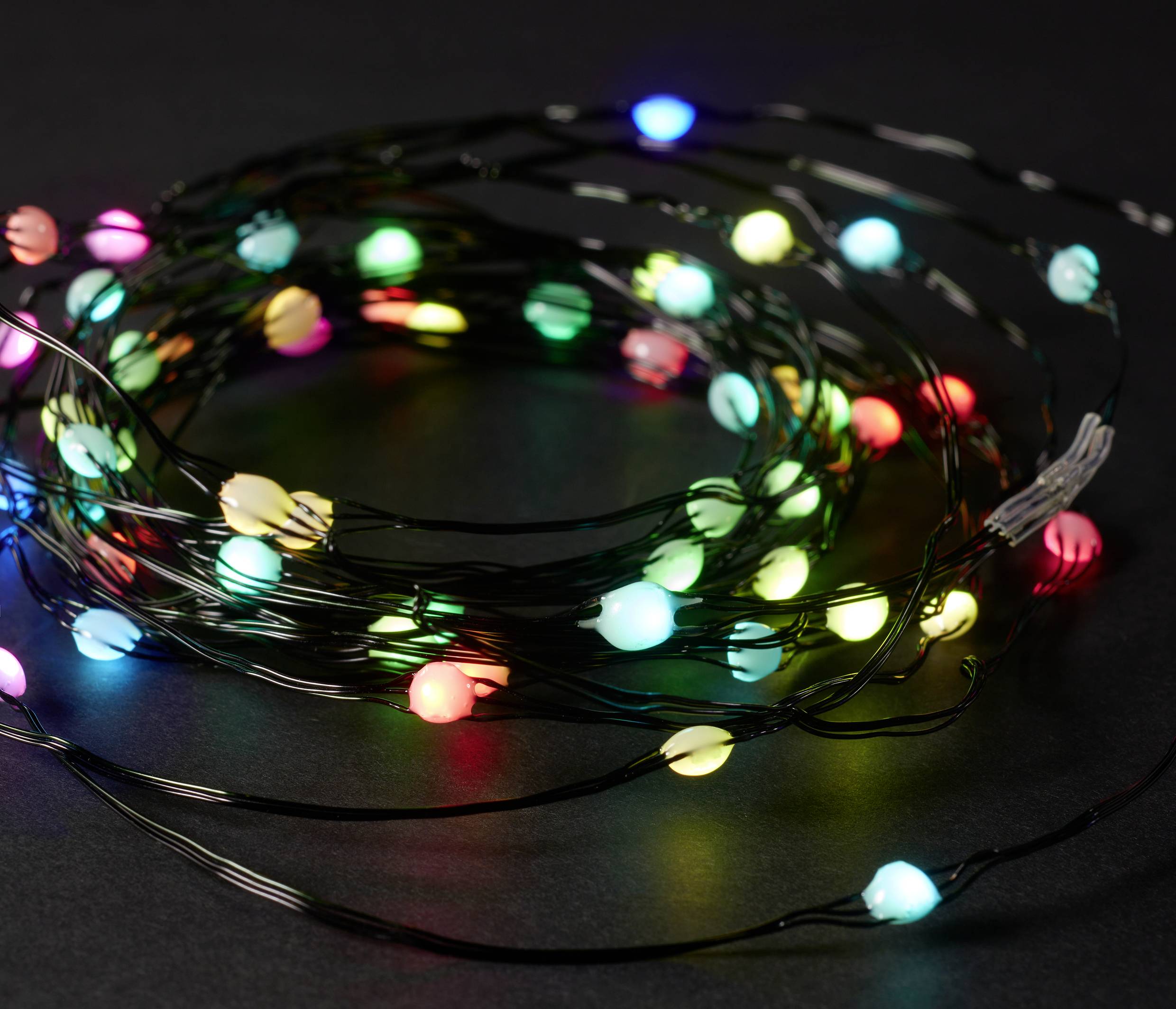 Eine Lichterkette mit bunten LED-Leuchten in verschiedenen Farben auf schwarzem Hintergrund.