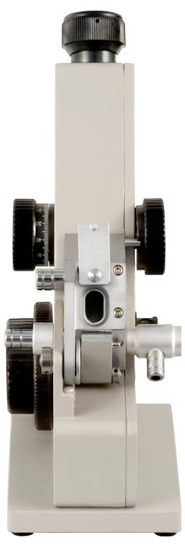Seitenansicht eines kleinen mechanischen Geräts oder Instruments mit einem beigen Gehäuse, schwarzem Einstellknopf oben und sichtbaren Zahnrädern und Rädern.