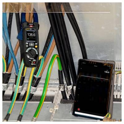 Elektrisches Schaltfeld mit unter Spannung stehenden Leitungen und Stromzange mit Anzeige von 136,6 A; ein Tablet spiegelt die Stromstärkeanzeige zur Überwachung.