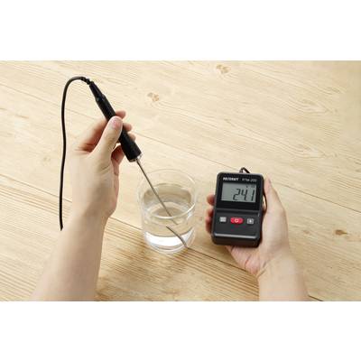 Eine Person misst die Wassertemperatur in einem Glas mit einem digitalen Thermometer, das '24.1' Grad anzeigt.