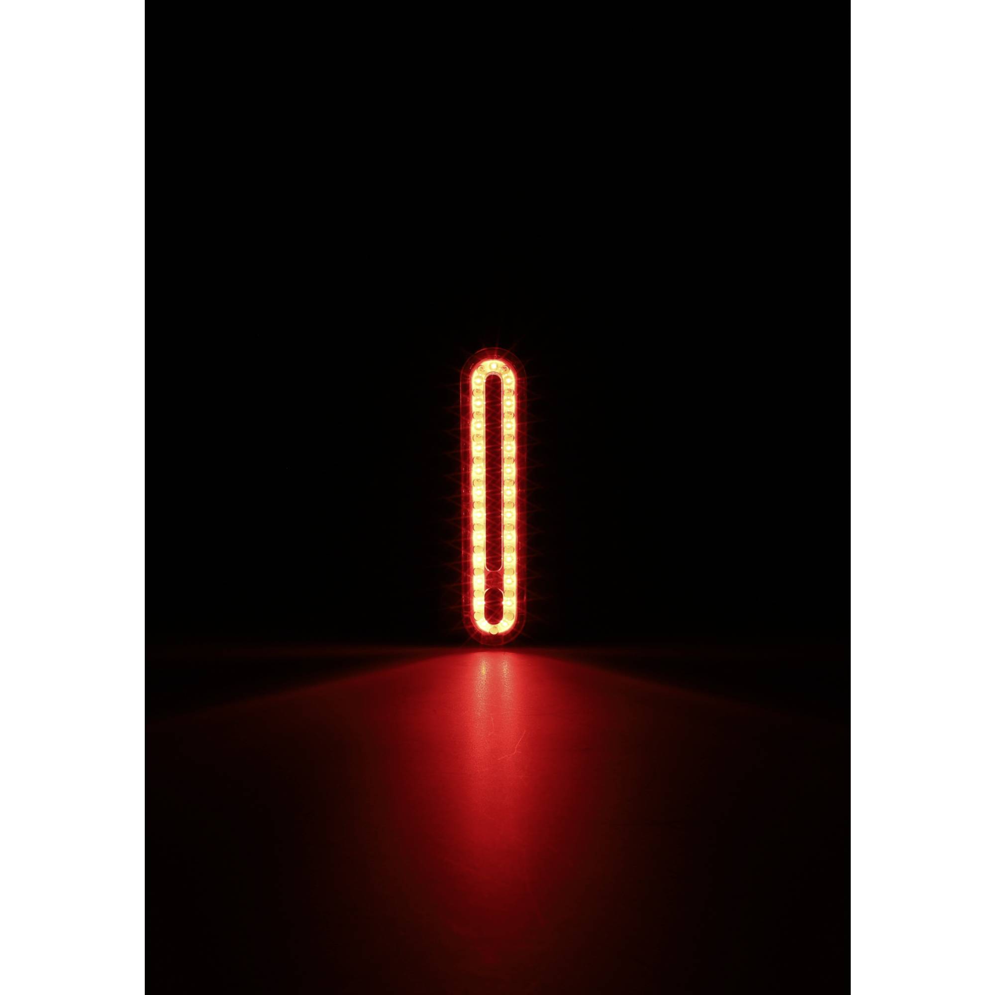 Ein helles, vertikales, rotes Licht in der Dunkelheit, das wie eine stehende Linie aussieht.