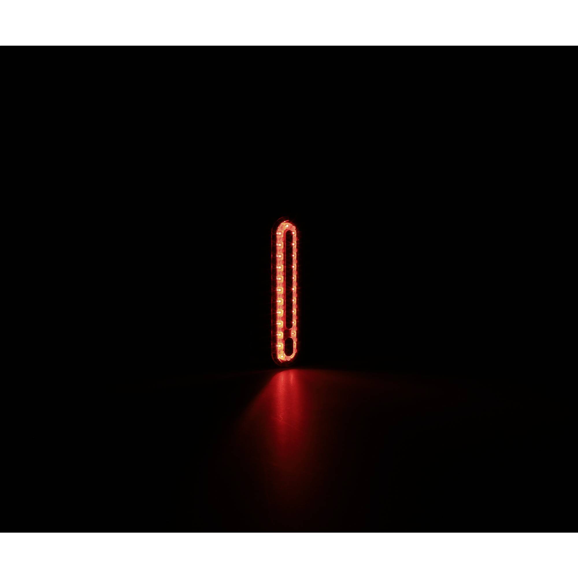 Ein rotes Licht leuchtet vertikal in der Dunkelheit. Es strahlt nach unten auf die Oberfläche.