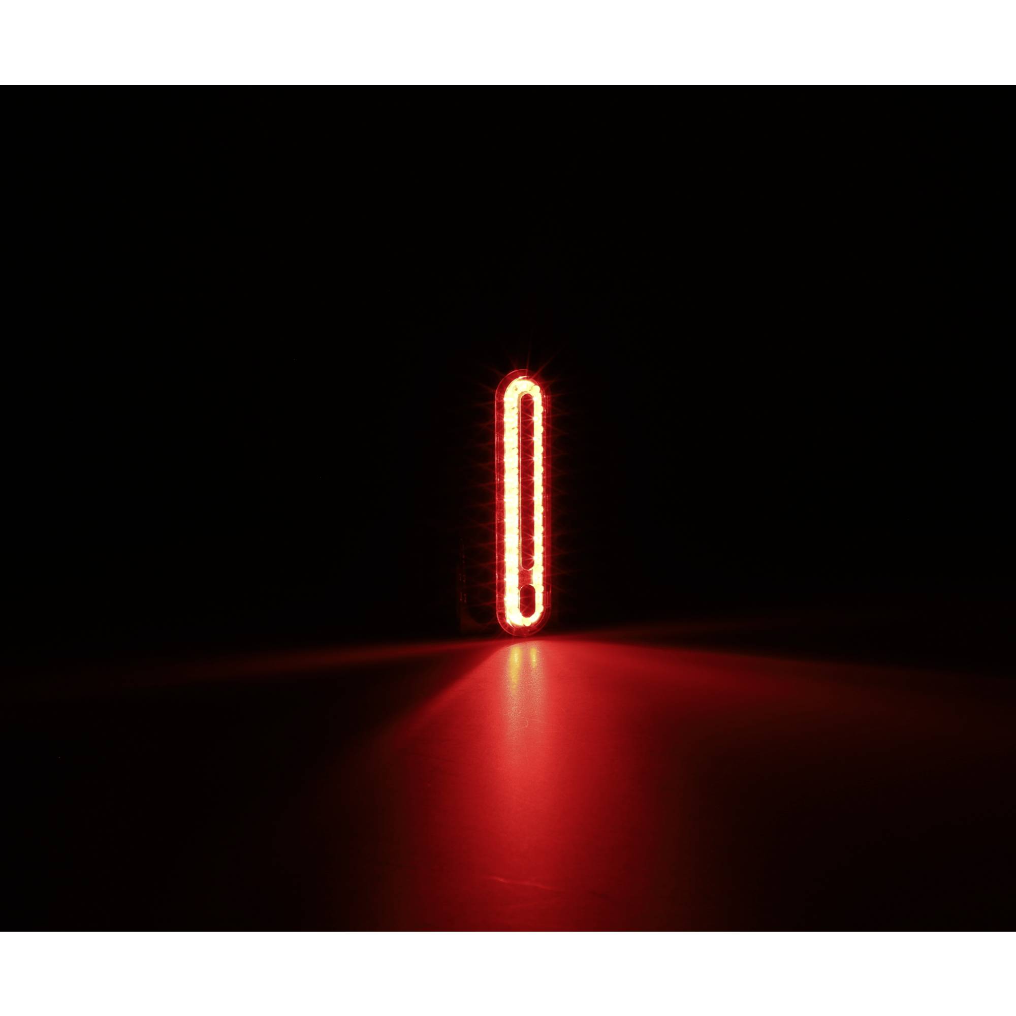 Rotes, vertikales LED-Licht in der Dunkelheit, das auf einer Oberfläche reflektiert wird und einen leuchtenden Streifen erzeugt.