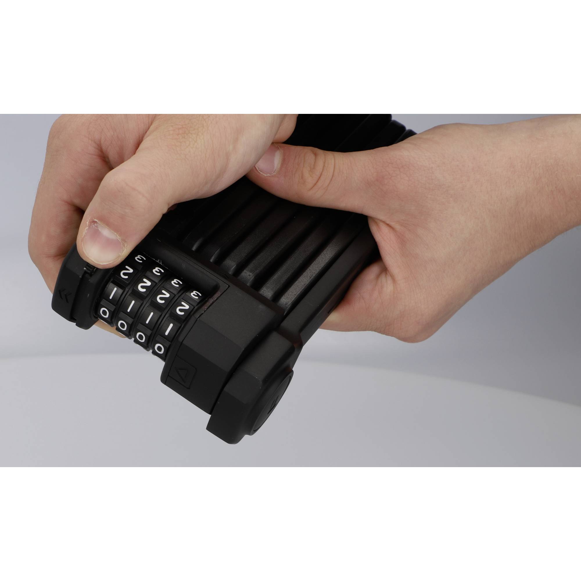 Eine Person hält ein Fahrradschloss mit Zahlenschloss, wobei die eingestellte Kombination sichtbar ist.