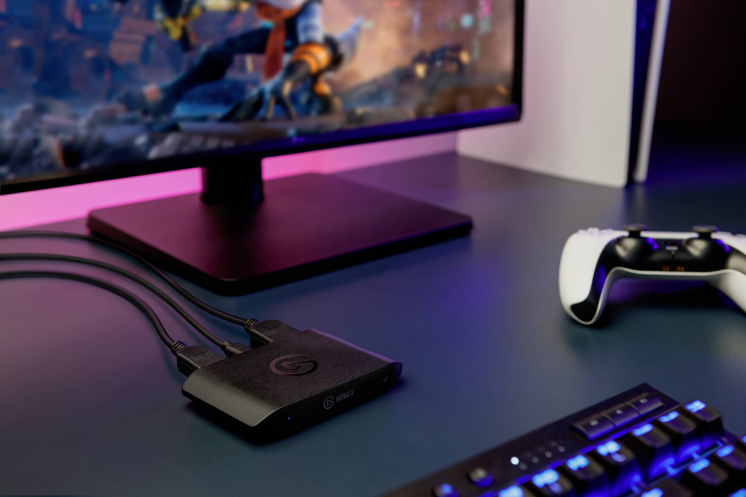 Ein Monitor zeigt ein Videospiel, daneben ein Gaming-Controller und eine Streaming-Box auf einem Schreibtisch. 