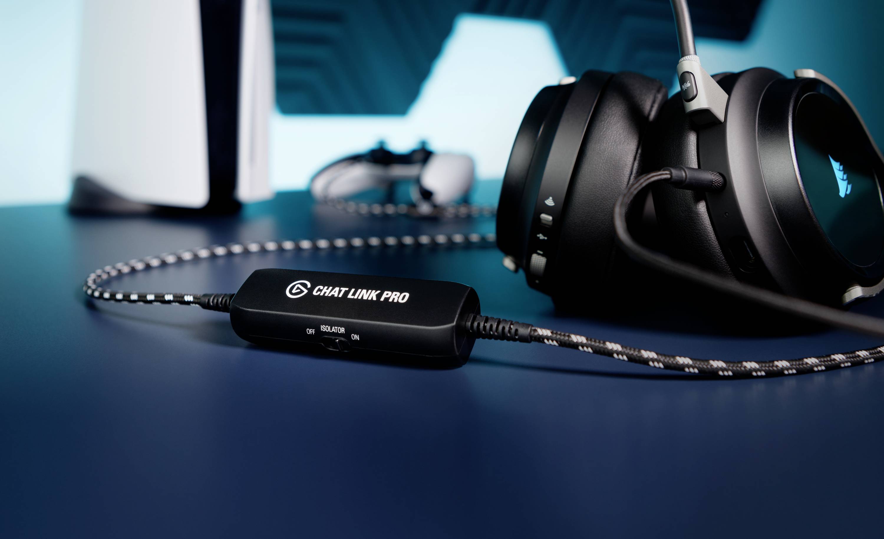 Ein Headset mit Kabel, verbunden mit einem Gerät namens 'Chat Link Pro', liegt auf einem Tisch. Im Hintergrund unscharf eine Konsole.