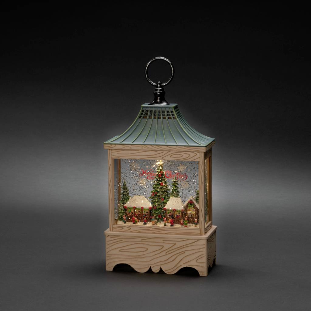 Eine Schneekugel mit einem Weihnachtsbaum und kleinen Häusern im Inneren, umgeben von schneebeladenen Tannen auf einem dekorativen Sockel.