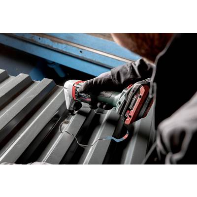 Person schneidet mit einem Metabo Elektrowerkzeug ein Wellblech, umgeben von metallischer Umgebung.