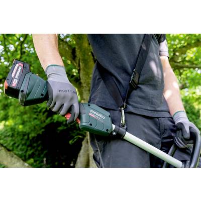 Eine Person hält eine grüne Akku-Gartenschere mit einem Metabo-Logo in einem grünen Garten. Trägt dunkle Kleidung und Handschuhe.