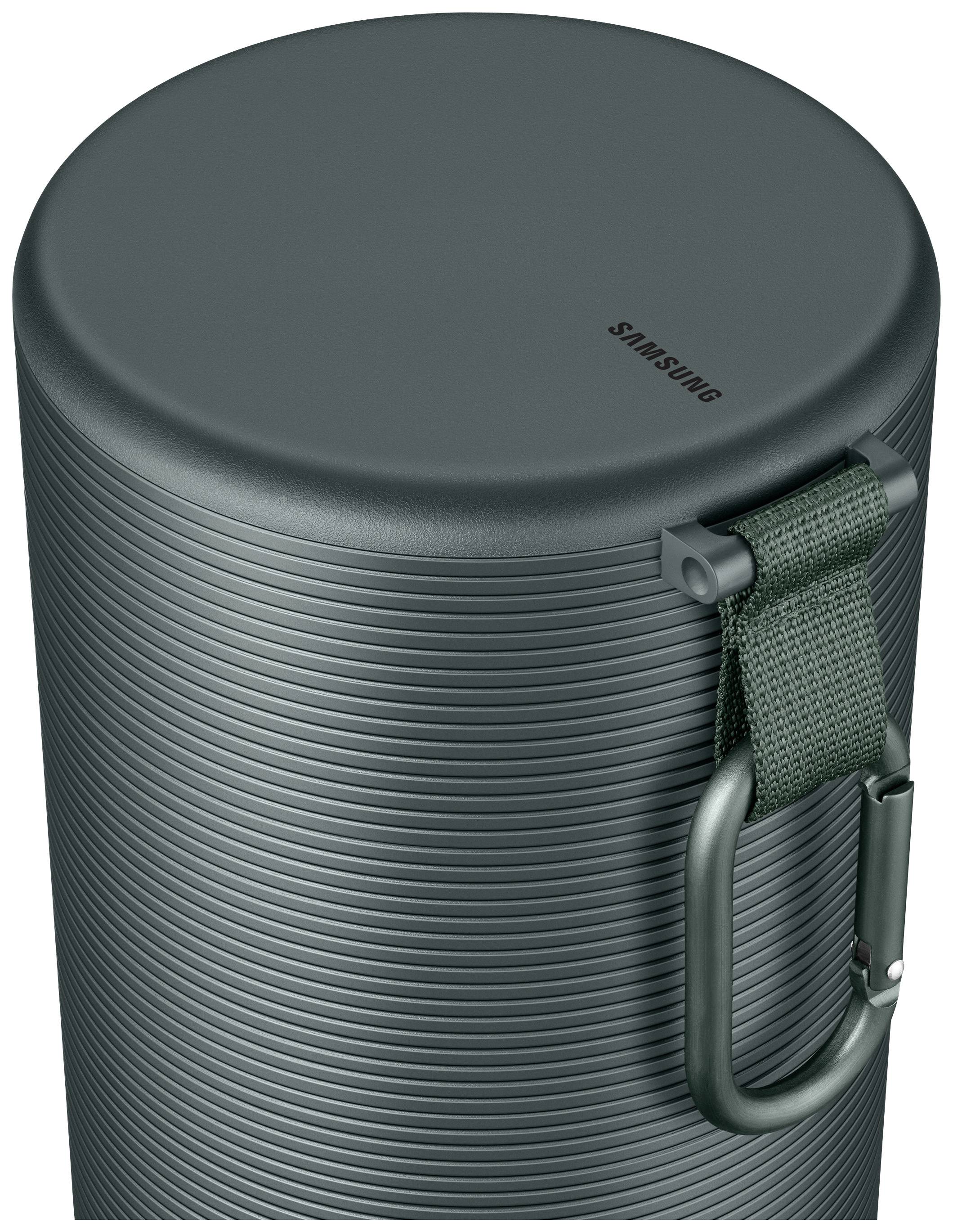 Ein grüner, zylindrischer Lautsprecher mit Textur, Halteriemen und Karabinerhaken. Oben ist das Samsung-Logo sichtbar.