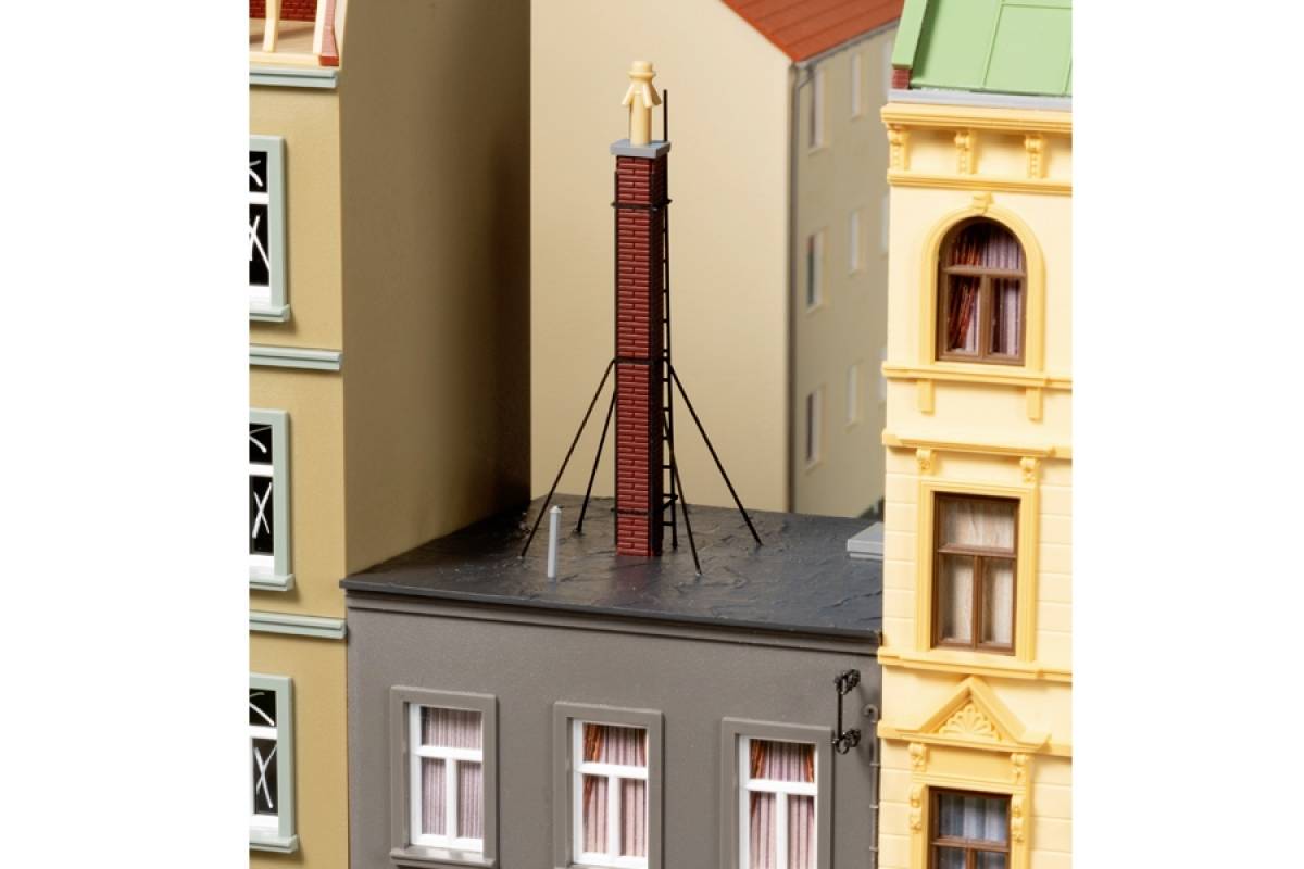 Modell einer Stadtszene mit Gebäuden und einem Schornstein auf einem Dach.