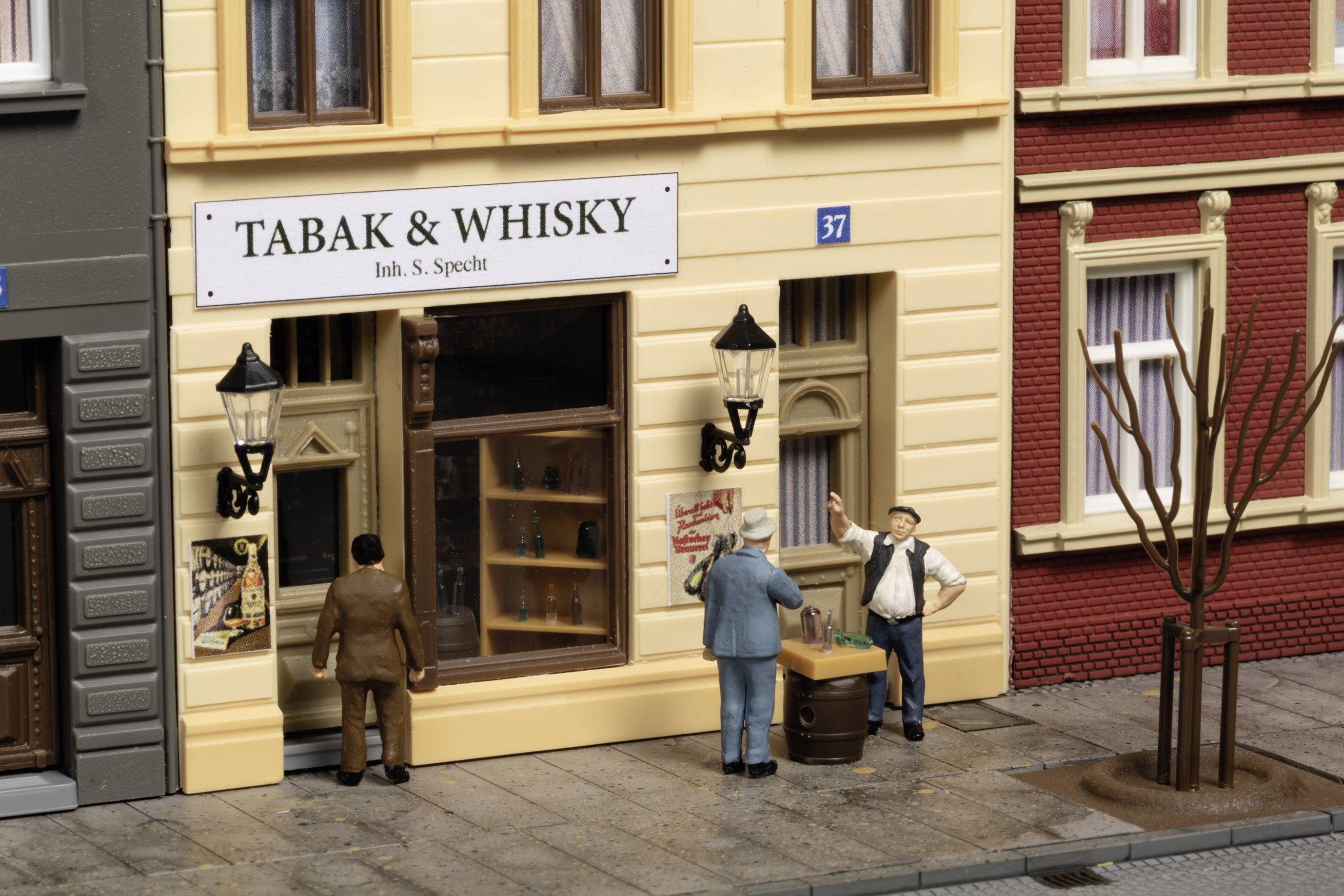 'Drei Figuren vor einem Geschäft mit dem Schild "Tabak & Whisky". Eine Person zeigt auf eine Ware auf einem Fass. Stadtstraße im Hintergrund.'
