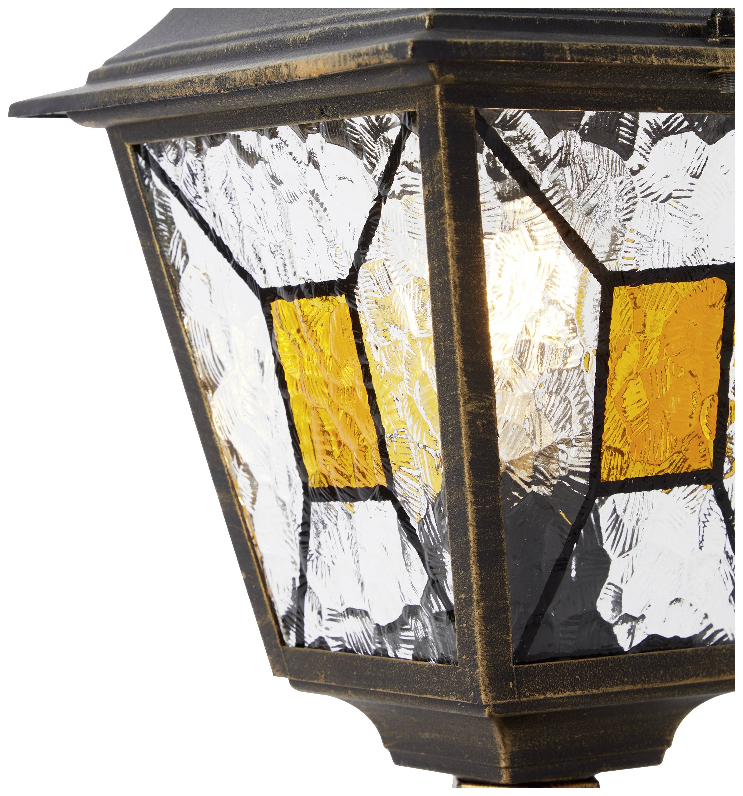 Eine antike Wandlaterne mit schwarzem Metallrahmen und dekorativen, farbigen Glasplatten. Sie leuchtet warm und erzeugt ein gemütliches Ambiente.
