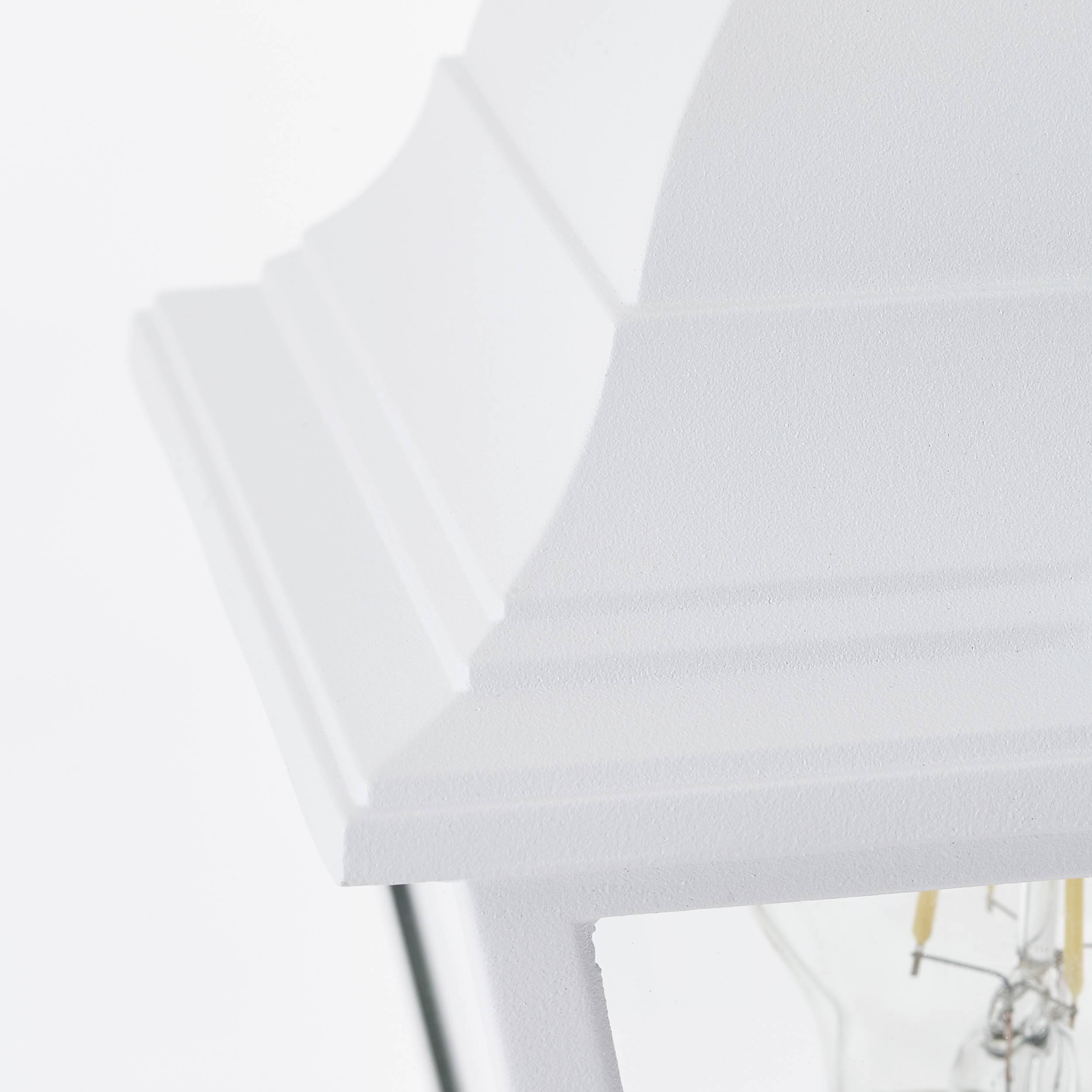 Weiße, dekorative Laterne teilweise sichtbar, hängt an einem schwarzen Pfosten. Minimalistisches Design, dient als Lichtquelle.