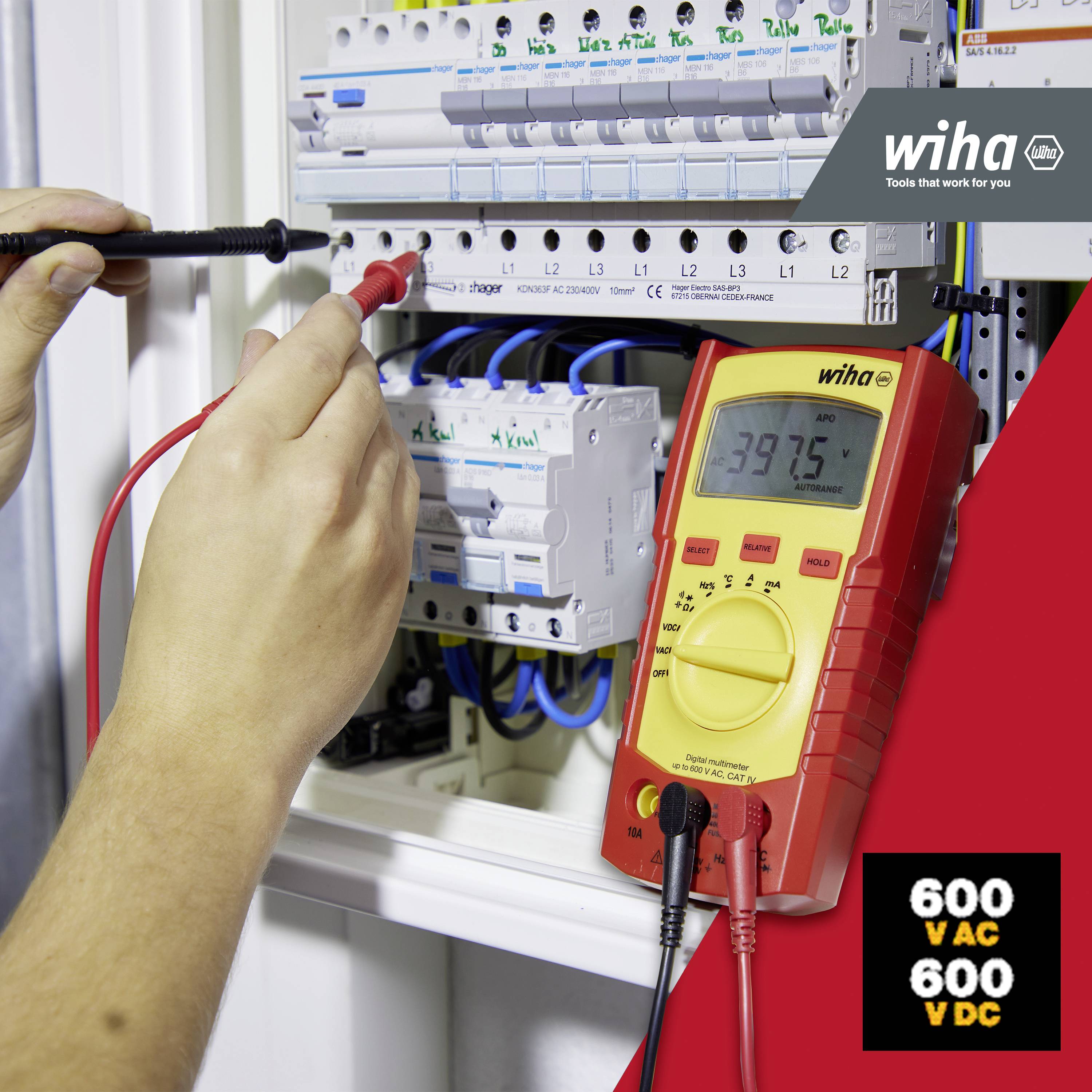 Person misst Spannung in einem Elektrokasten mit einem Multimeter. Das Display zeigt 397,5 V. Rechts unten steht '600 VAC 600 VDC'.