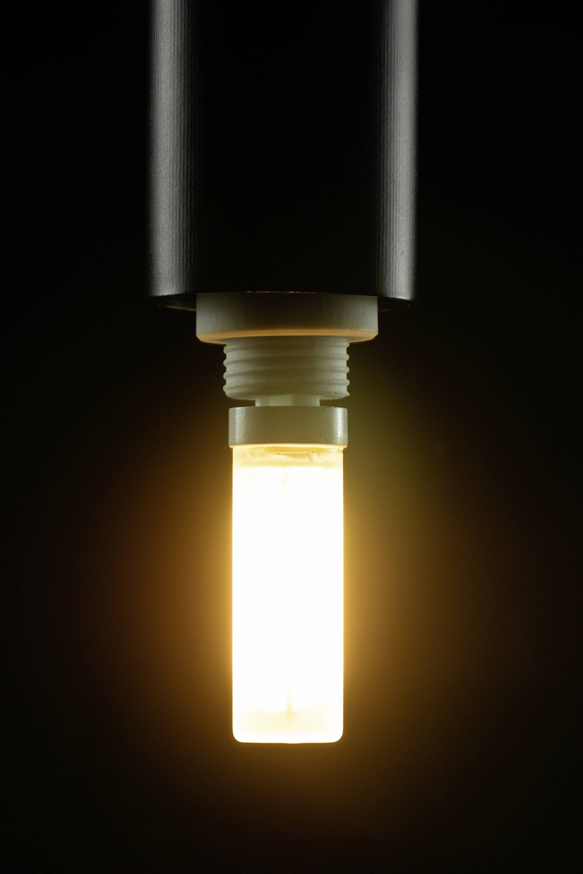 Eine glühende Glühbirne leuchtet warm in einem dunklen Raum und strahlt sanftes Licht aus.