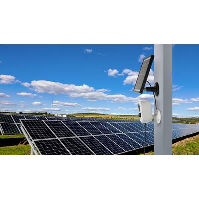 Solaranlage auf einem Feld unter blauem Himmel. Im Vordergrund eine Kamera an einem Pfosten.