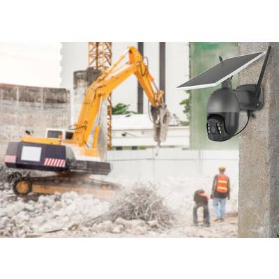 'Überwachungskamera mit Solarzelle' überwacht Baustelle. Im Hintergrund Bagger und zwei Bauarbeiter mit Schutzhelmen bei Abbrucharbeiten.