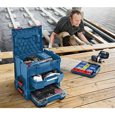 Ein Arbeiter repariert Holzplanken auf einem Steg. Im Vordergrund sind geöffnete Werkzeugkästen und Elektronikwerkzeuge zu sehen.