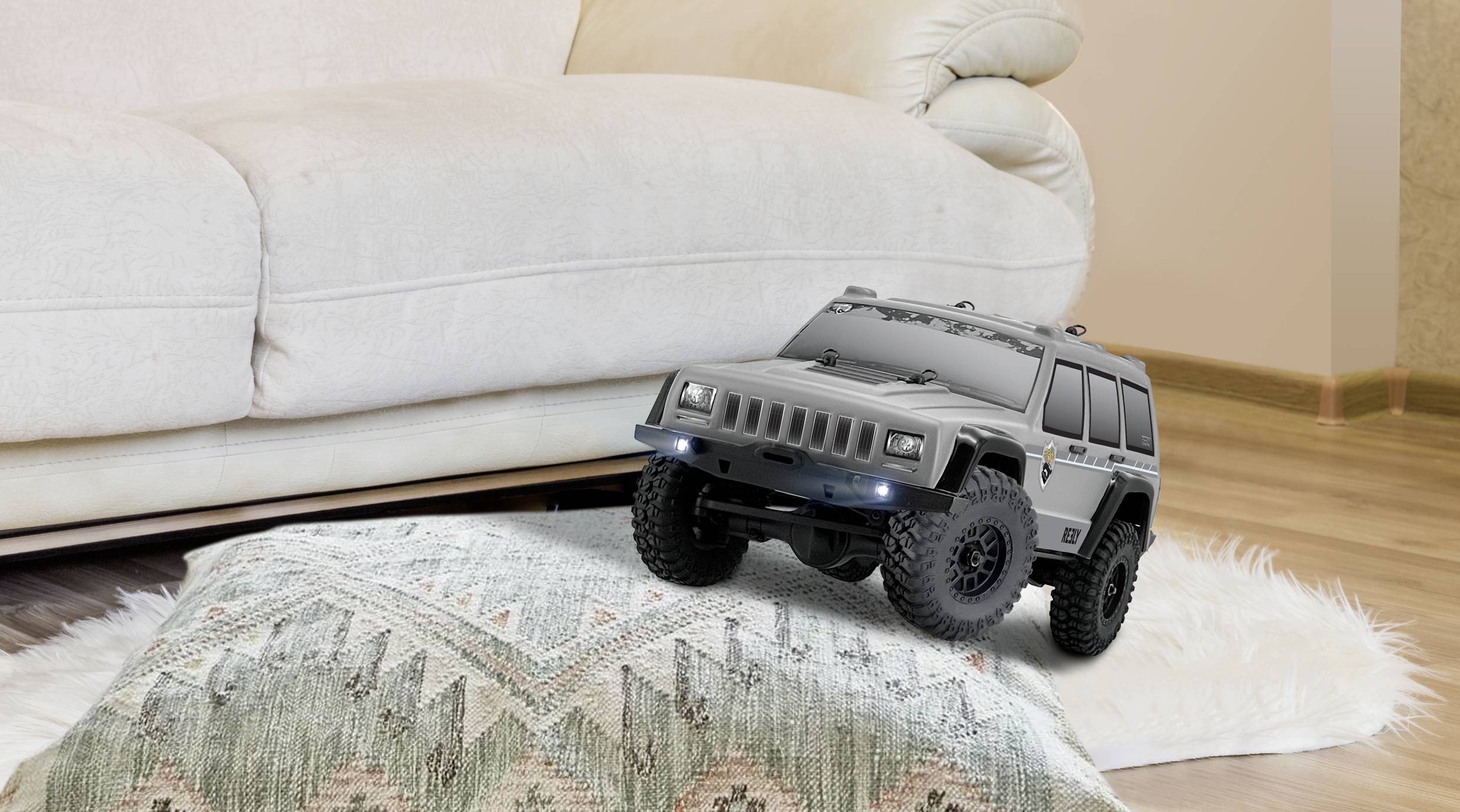 Ein ferngesteuertes Spielzeugauto im SUV-Stil fährt über ein Kissen auf einem hellen Teppich vor einem weißen Sofa in einem Wohnzimmer.