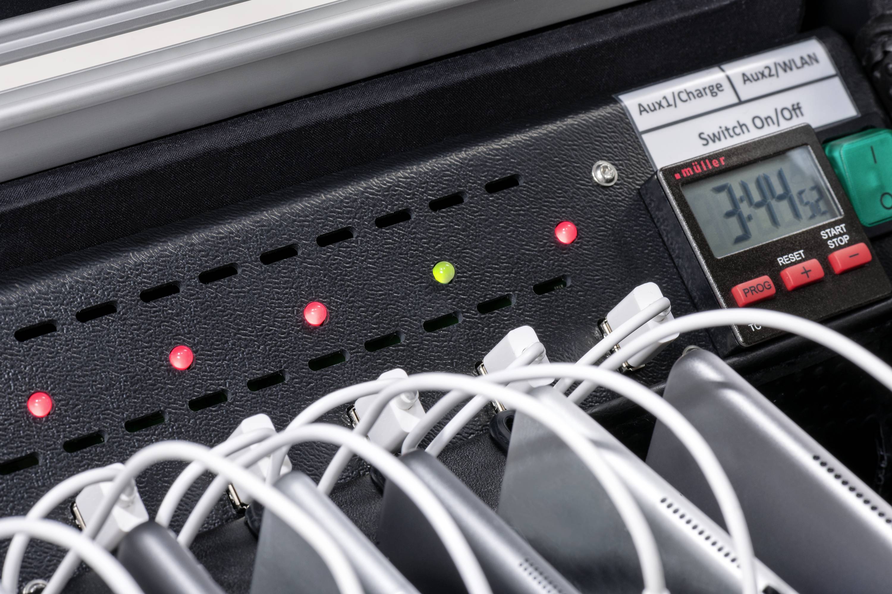 Mehrere Geräte geladen, angeschlossen an eine Steckdosenleiste mit LED-Anzeigen. Ein Display zeigt eine Ladezeit von '3:44'.
