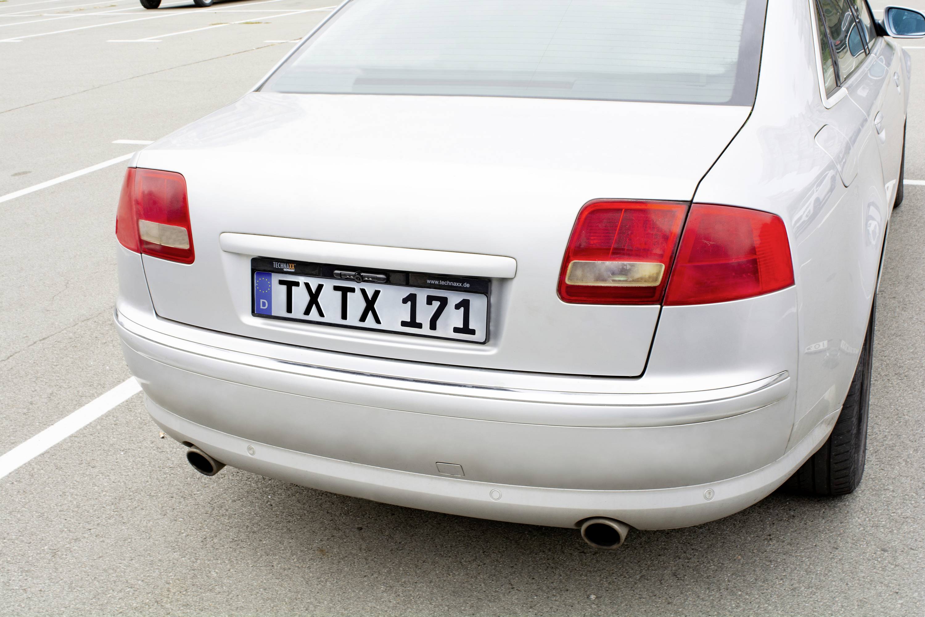 Ein silbernes Auto auf einem Parkplatz, von hinten gesehen. Das Kennzeichen zeigt 'TXTX 171'.