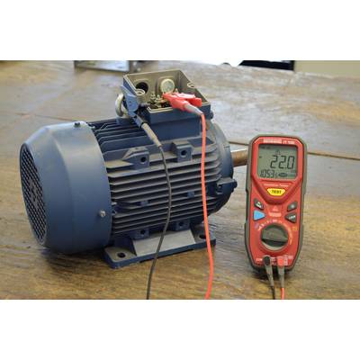 Ein Elektromotor auf einem Tisch wird mit einem Multimeter gemessen, das einen Wert von 22.0 Ohm anzeigt.