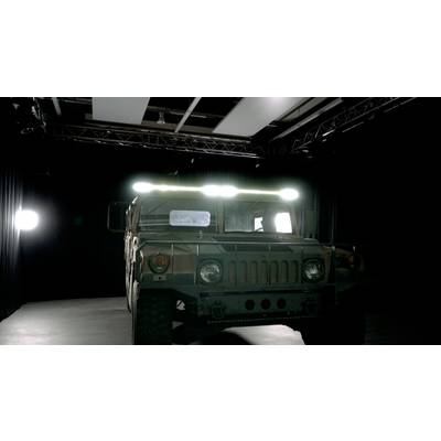 Ein gepanzertes Militärfahrzeug steht in einem dunklen Raum, umgeben von Scheinwerfern. Das Licht hebt seine robuste Bauweise hervor.