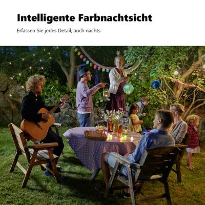 Eine Gartenfeier bei Nacht mit Musik und Lichtern. Menschen sitzen und stehen um einen Tisch, einige unterhalten sich, andere genießen die Atmosphäre.