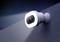 Weiße Überwachungskamera mit integriertem Licht, schräg an einer Wand montiert, strahlt hellen Lichtstrahl in die Dunkelheit.