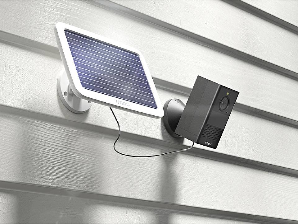 Eine Überwachungskamera mit Solarpanel ist an einer Hauswand montiert. Das Solarpanel versorgt die Kamera mit Energie.