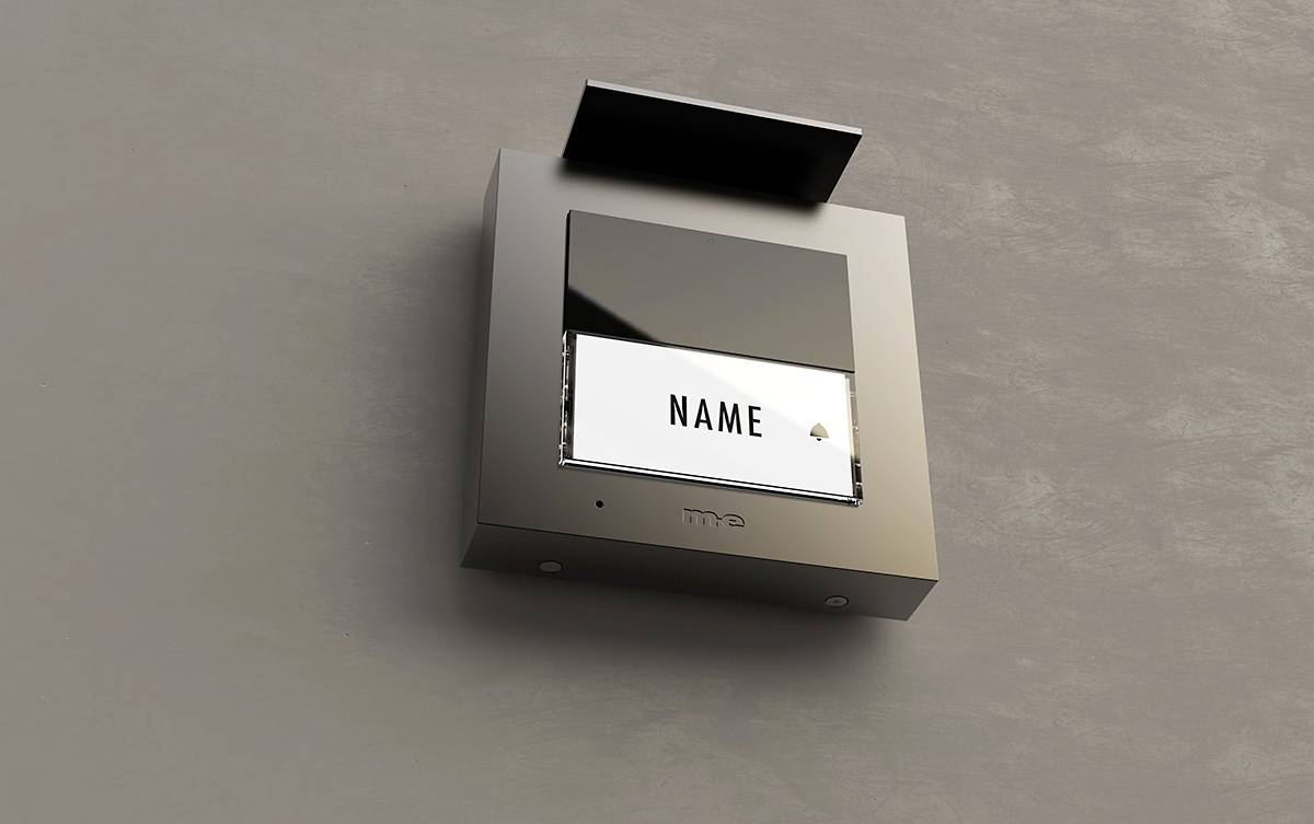 Eine modern designte Türklingel an einer Wand, mit einem herausziehbaren Namensschild, auf dem 'NAME' steht.
