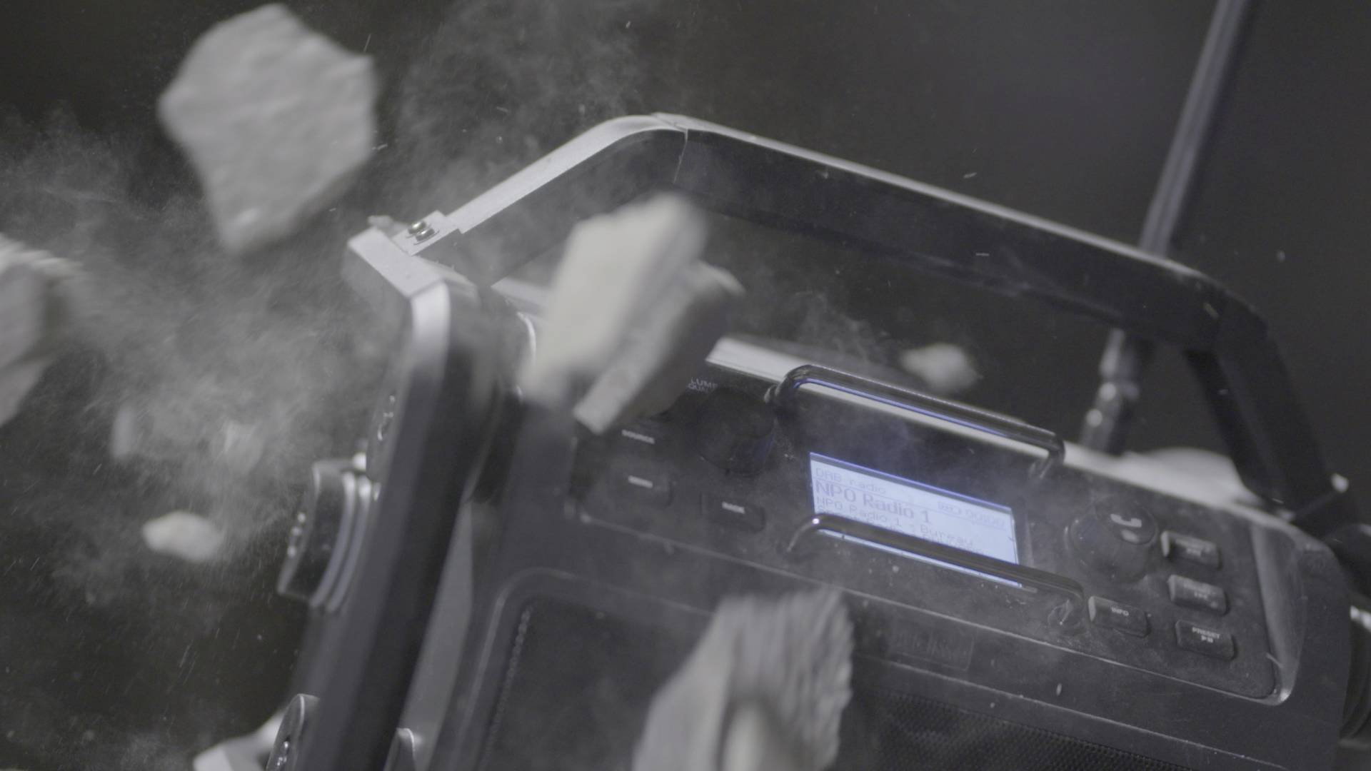 Ein robustes Radio wird von herabfallenden Trümmern getroffen, illustriert die Strapazierfähigkeit des Geräts unter extremen Bedingungen.