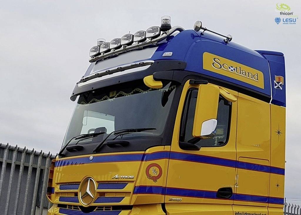 Gelber und blauer Lastwagen mit der Aufschrift 'Scotland' auf der Fahrerkabine, geparkt in einer industriellen Umgebung.