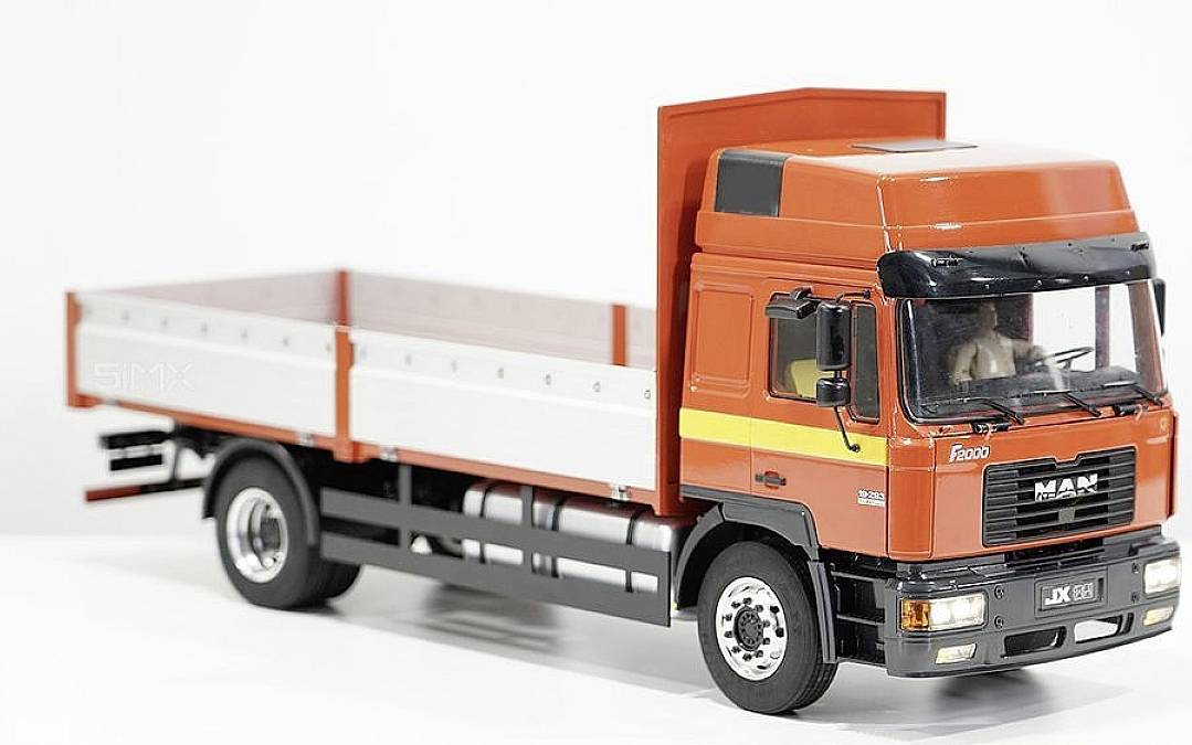 Ein orangener LKW-Modell mit rotem Führerhaus und offener Ladefläche steht seitlich auf weißem Hintergrund.