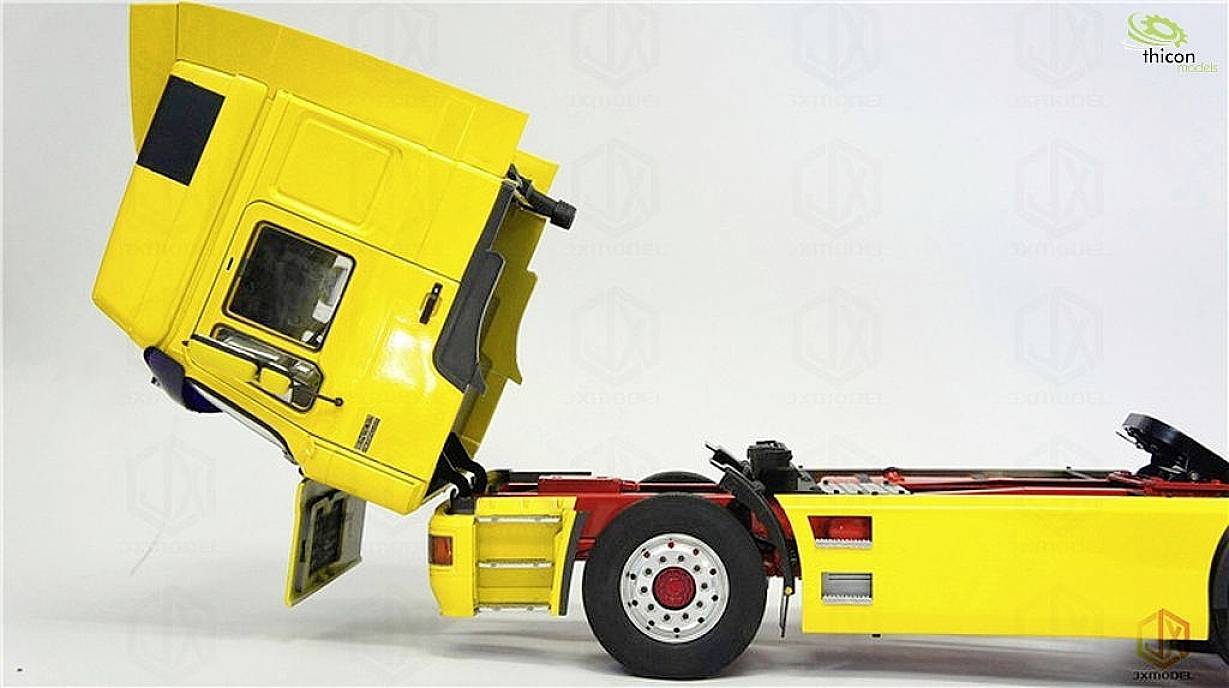 Gelber Lastwagen mit geöffneter Fahrerkabine zeigt technischen Aufbau. Die Kabine ist nach vorne gekippt, um den Motor freizulegen.