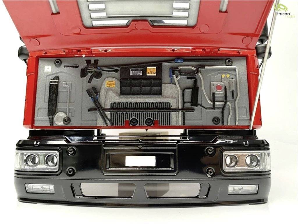 Rote Motorhaube eines LKW-Modells geöffnet, zeigt detailliertes Innenleben mit Kabeln, Ventilator und Werkzeugen.