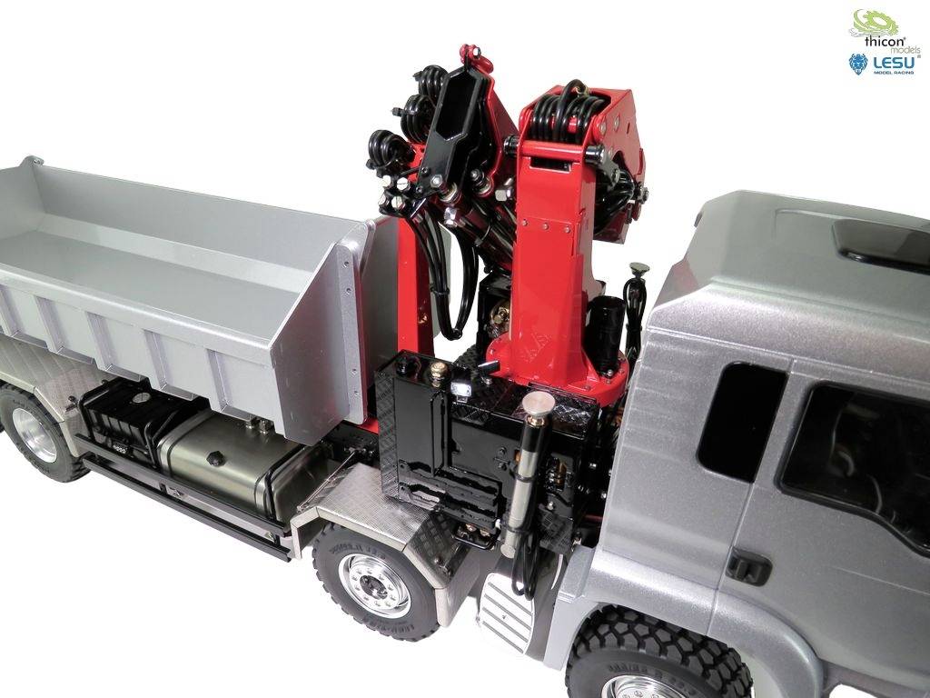 Ein Modell-LKW mit Kranarm auf der Ladefläche, der in einer Werkstattumgebung steht. Der Kranarm ist rot und ausgefahren.