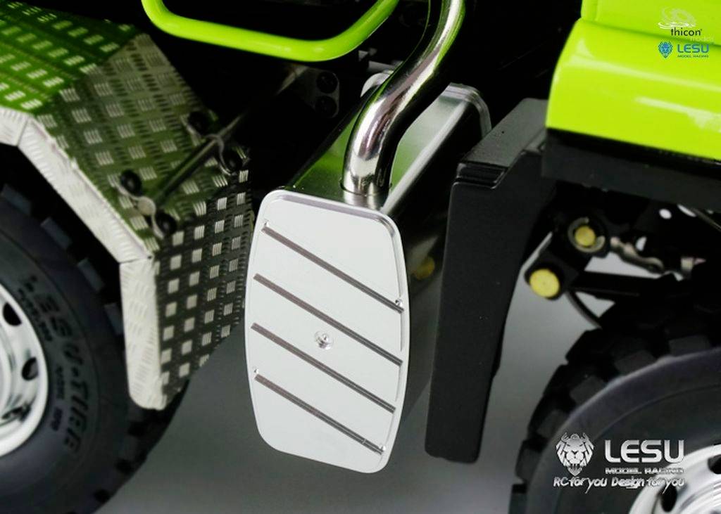 Nahaufnahme einer metallischen Fußstütze an einem Fahrzeug, daneben der Teil eines großen Reifens und ein grünes Karosseriestück.