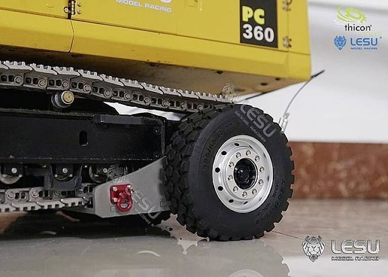 Spielzeugmodell eines gelben LKW mit Aufschrift 'PC 360'. Detailansicht zeigt Rad und Kettenantrieb. Marke 'LESU' auf dem Foto sichtbar.