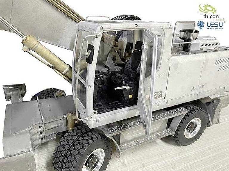 Ein detailliertes Modellfahrzeug, das einen Kran mit offenem Fahrerhaus zeigt. Links oben sind die Logos von 'thicon models' und 'LESU'.