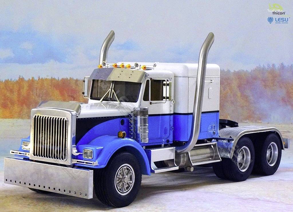 Großer blauer Lastwagen mit silbernem Kühlergrill und zwei vertikalen Auspuffrohren, auf einer verschneiten Landschaft im Hintergrund.