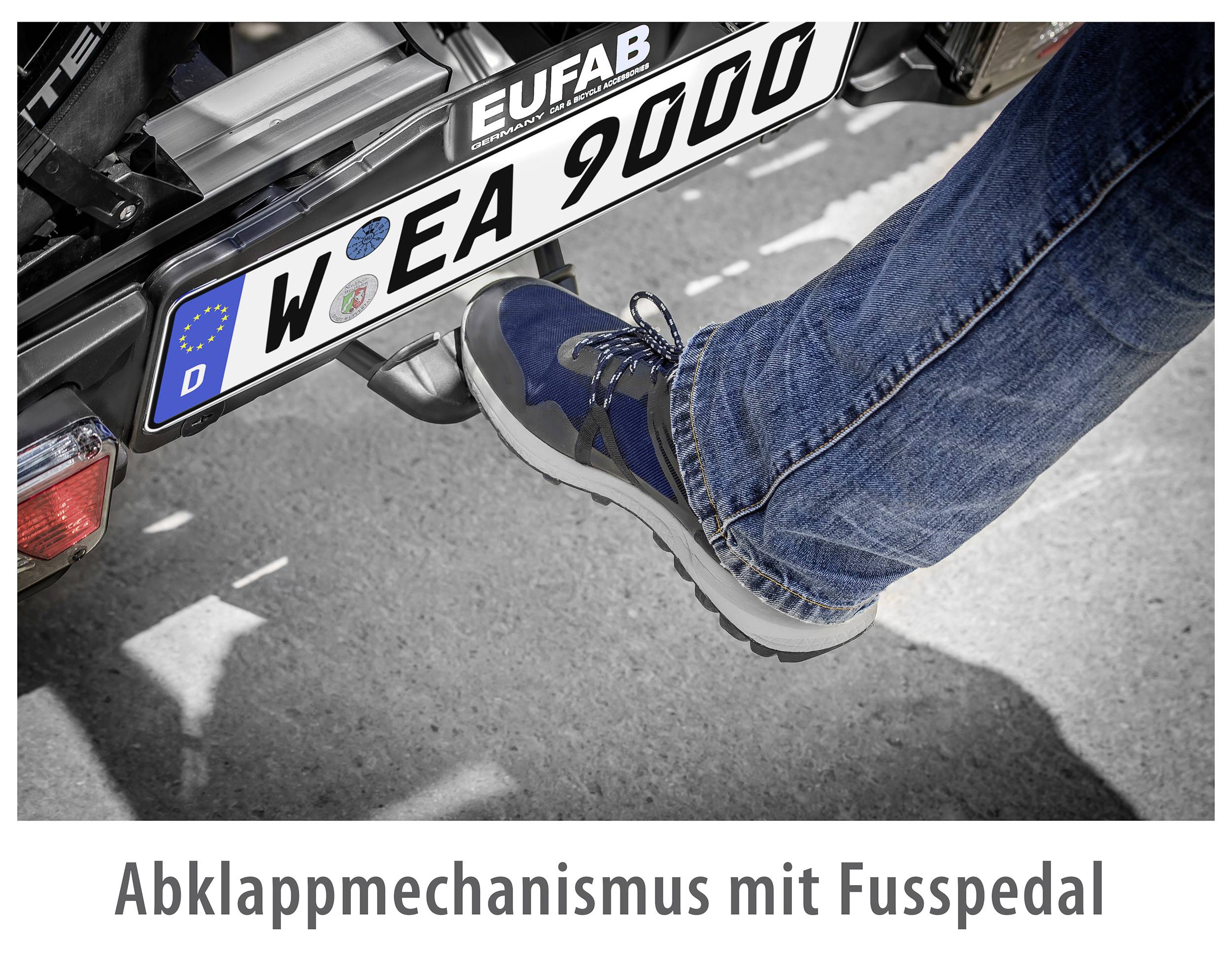 Ein Fuß tritt auf ein Pedal unter einem Kfz-Kennzeichen. Text unten: 'Abklappmechanismus mit Fusspedal'.