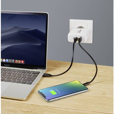 Laptop und Smartphone auf einem Holztisch. Beide Geräte sind über ein Ladegerät an einer Steckdose angeschlossen. смартфон zeigt grünen Akku.