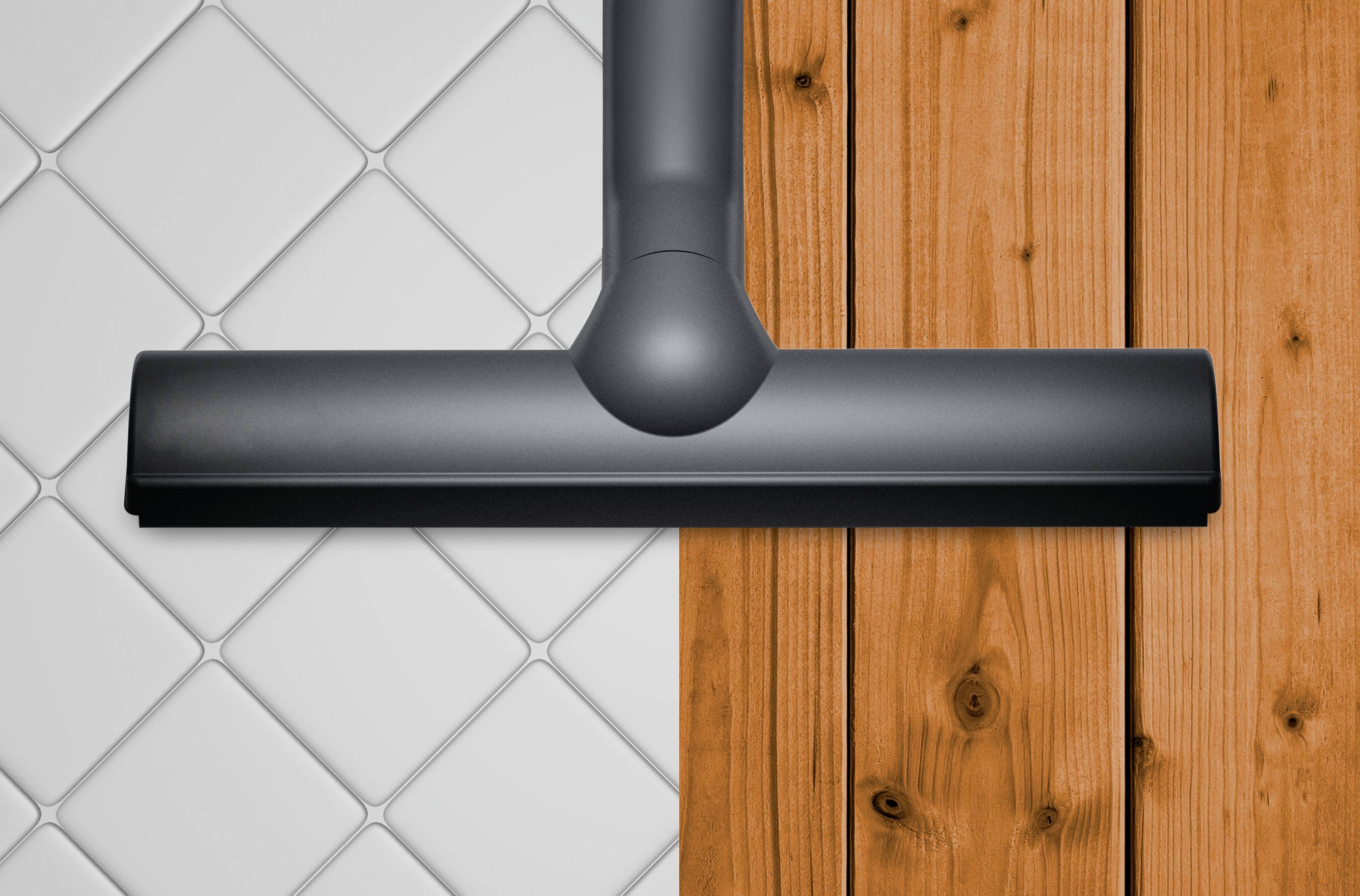 Ein Staubsaugerkopf reinigt unterschiedliche Oberflächen, links weiße Fliesen und rechts helles Holz.