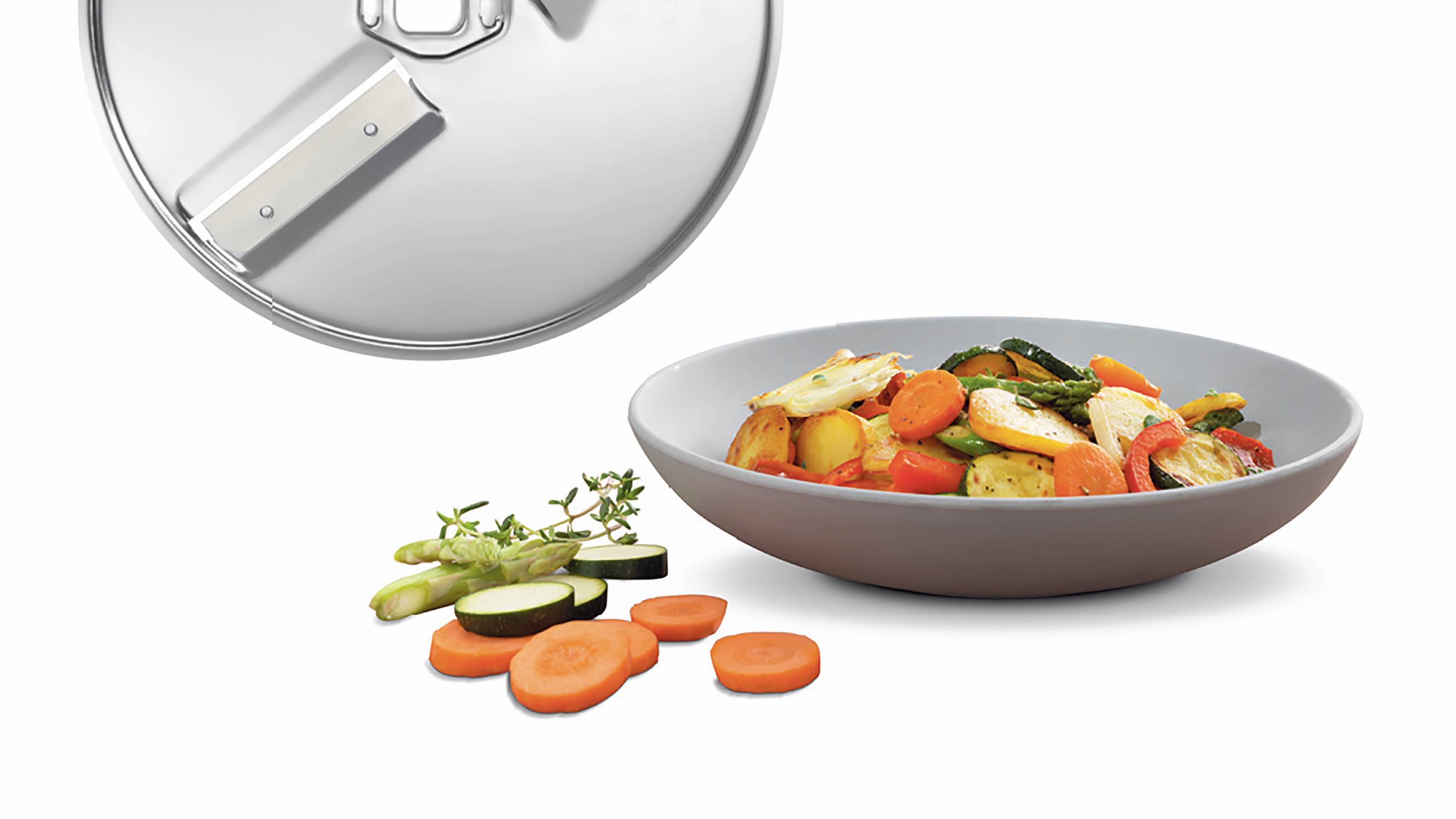 Gemüsepfanne mit Zucchini, Karotten und Spargel in einer grauen Schüssel, daneben geschnittenes Gemüse und ein Topfdeckel.