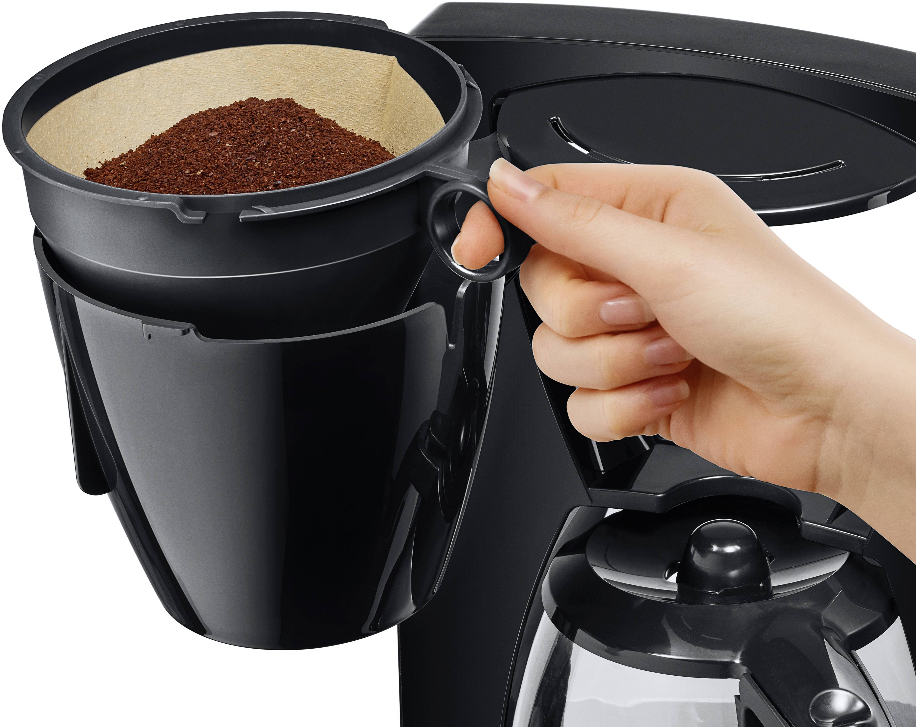 Eine Hand hält einen schwarzen Kaffeefilter mit Kaffeepulver, der in eine Kaffeemaschine eingesetzt wird.